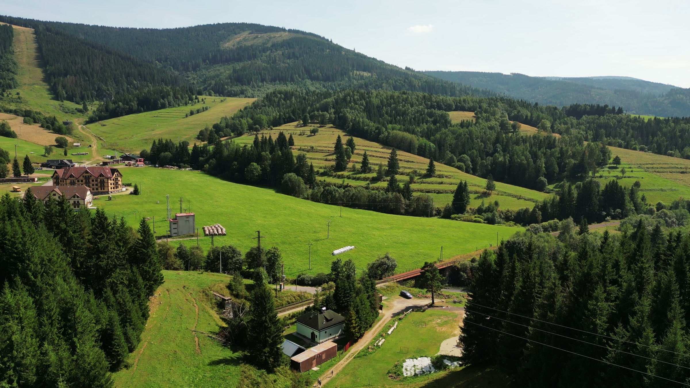 Luftaufnahme einer Mittelgebirgslandschaft mit Wiesen, Tannenwald und Hügeln