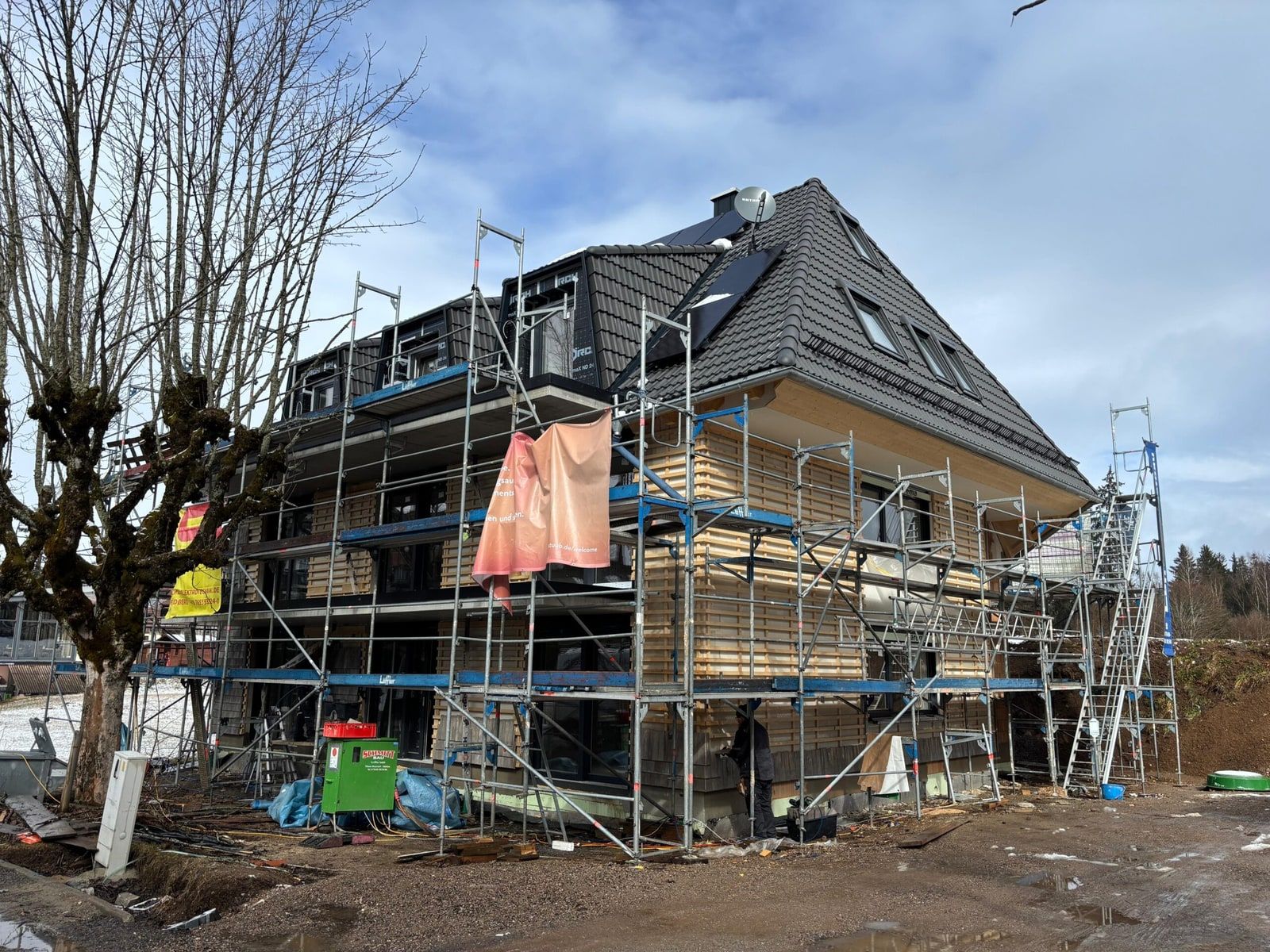Neubau im Rohbau mit Gerüst, das Dach ist bereits eingedeckt
